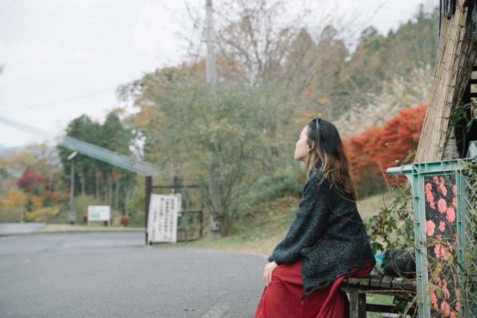 秋の穏やかな日本の田園風景の中で屋外に座っている女性。