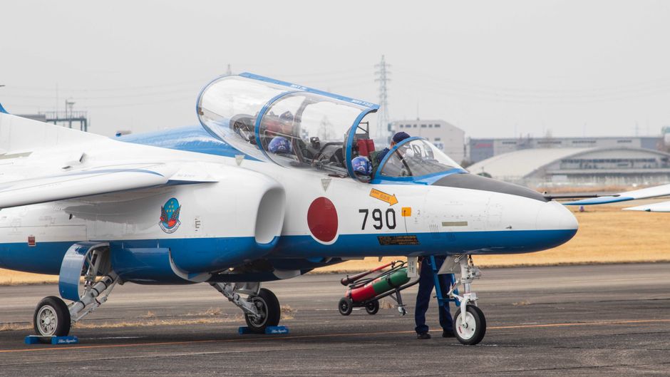 日本の国旗を掲げた練習機が飛行場の準備のためにタキシング中。