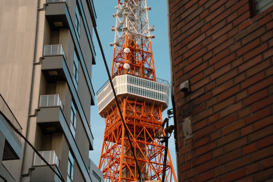 澄み切った空の下、街のビル群に囲まれた象徴的な東京タワーが垣間見える。