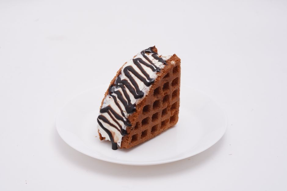 白いお皿にクリームとチョコレートソースをトッピングした美味しいチョコレートワッフル。