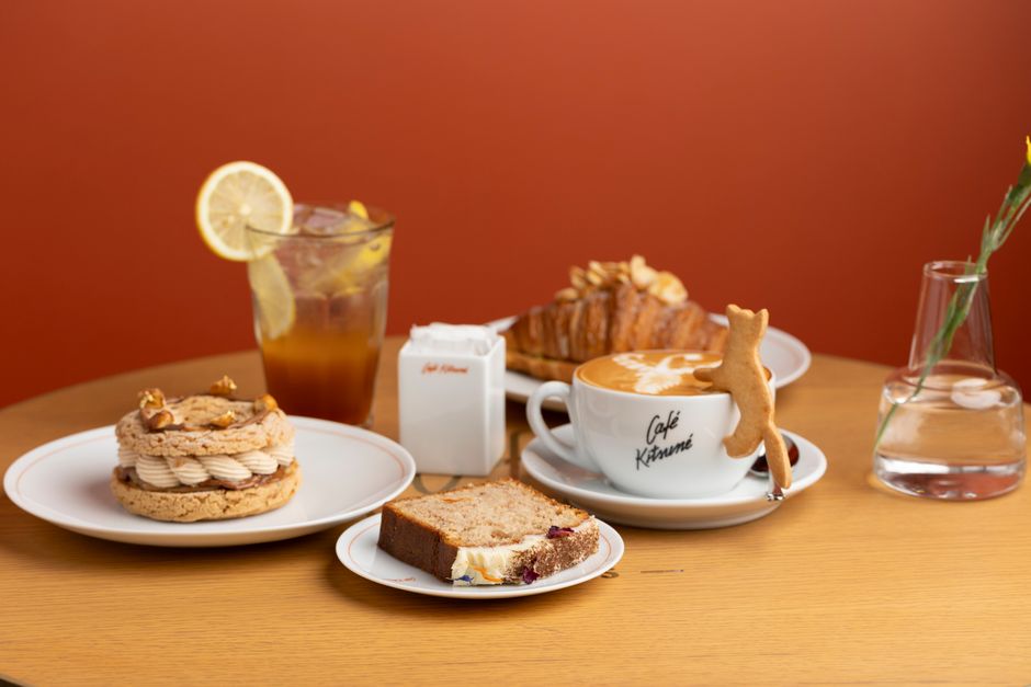 暖かい背景を背景に、ペストリー、コーヒー、アイスティーを置いたスタイリッシュなカフェテーブル。