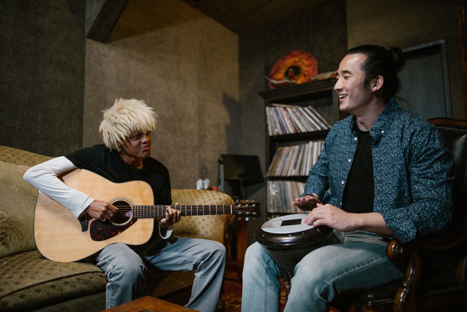 2人のミュージシャンが居心地の良い音楽スタジオでギターとドラムを楽しんでいます。