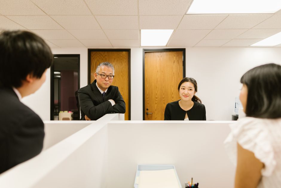 オフィスで話し合うビジネスチーム（上司を「さん」付けで呼ぶ職場のイメージ）